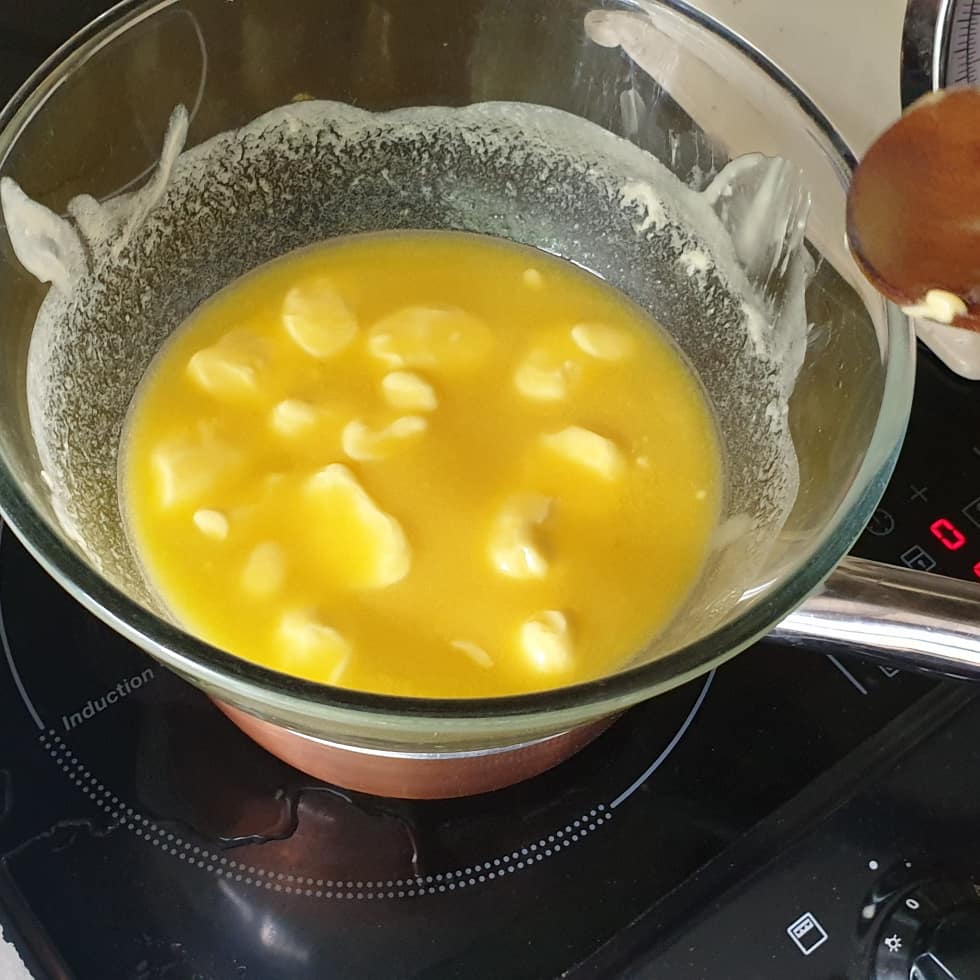 Melting butter in a bowl over a pan of hot water.
